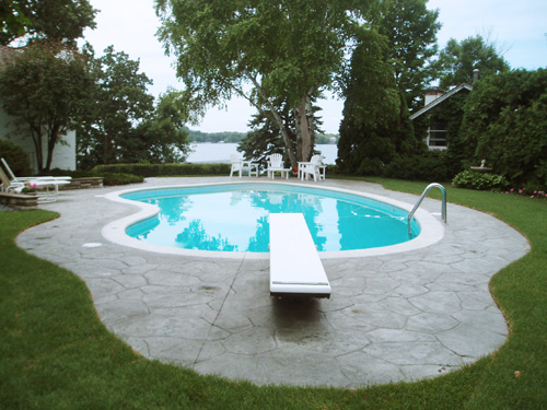 A backyard pool after resurfacing, the patio freshly poured and the water bright and clean.