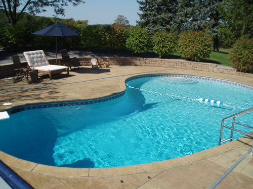 An in-ground pool with new tile and coping running along a tidy Twin Cities backyard.