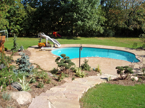 A backyard pool after a Northern Aire renovation, surrounded by new patio.