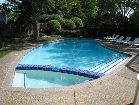 A renovated in-ground pool with fresh decking and clear blue water.
